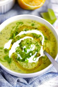 a white bowl filled with soup and topped with sour cream, green onions and cilantro