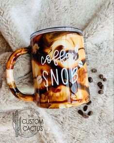 a coffee mug with the words coffee snoe on it sitting next to some coffee beans