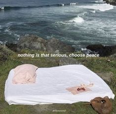 there is a white blanket on the ground by the ocean with words about nothing that serious, choose peace