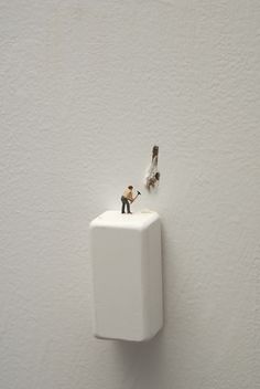 a tiny figurine is standing on top of a toilet paper dispenser