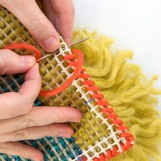 two hands are working on a piece of fabric that is being knitted with scissors