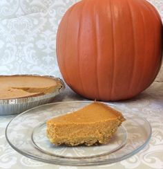 a piece of pumpkin pie sitting on top of a glass plate next to an orange pumpkin