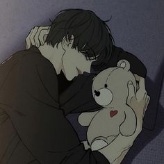 a man holding a teddy bear in his arms while sitting on the floor next to him