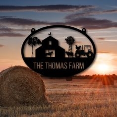 the thomas farm sign with hay bales in front of it and sunset behind it