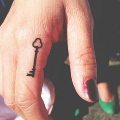 a person's finger with a small key tattoo on it