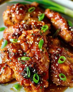 chicken wings with sesame seeds and green onions on a plate