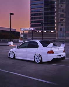 a white car parked in a parking lot next to tall buildings