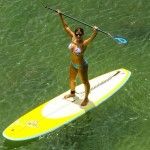 a woman on a surfboard in the water with her arms raised above her head