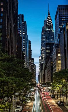 a city street filled with lots of tall buildings and cars driving down it's sides