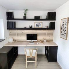 a desk with a computer on top of it next to black cabinets and shelves in a room