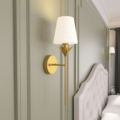 a white bed sitting next to a wall mounted lamp