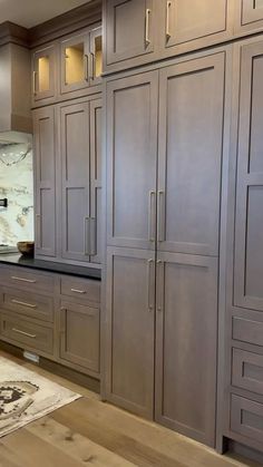 a kitchen with wooden cabinets and marble counter tops, along with an area rug on the floor