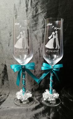 two wine glasses decorated with bride and groom's silhouettes, one is holding a blue ribbon