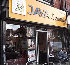 people sitting at tables in front of a storefront with the name java lounge on it