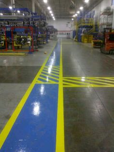 an empty warehouse with blue and yellow lines painted on the floor