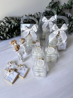 several small packages with white bows on top of a table next to cookies and candies