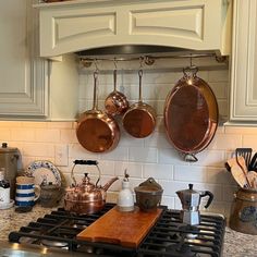 pots and pans are hanging on the wall above the stove