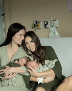 two women are sitting on a couch holding their newborn babies and smiling at the camera