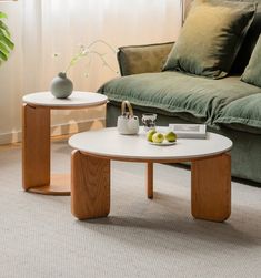 two coffee tables sitting on top of a carpeted floor next to a green couch