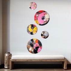 three circular mirrors hanging on the wall above a bench in front of a white wall