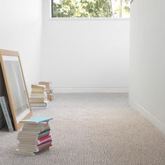 a pile of books sitting on the floor next to a mirror