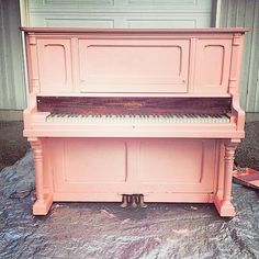 an old pink piano sitting in front of a garage