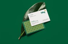 a business card sitting on top of a green leaf with the word hey printed on it