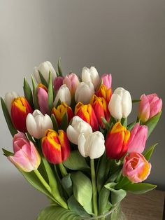 a vase filled with lots of different colored tulips on top of a table