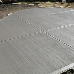 a skateboarder doing a trick in the air on a concrete surface with rocks and grass