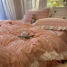 a pink bed with ruffled sheets and pillows