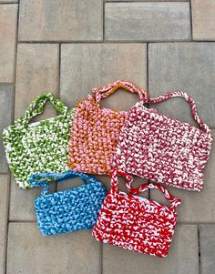 four purses sitting on top of a tiled floor next to each other in different colors