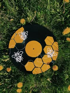 a black and yellow beehive with white bees on it sitting in the grass