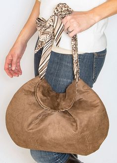 a woman holding a brown purse with a bow on it