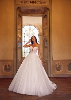 a woman in a white wedding dress posing for the camera with her hand on her head