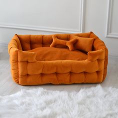 an orange dog bed sitting on top of a white rug