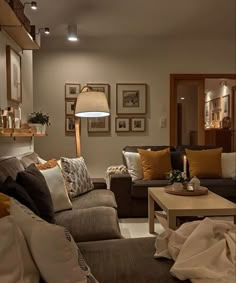 a living room filled with lots of furniture next to a lamp and pictures on the wall