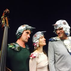 three people wearing paper hats and standing next to each other in front of a bass