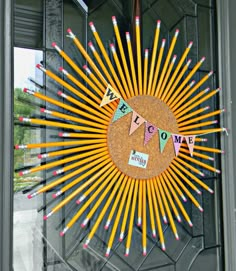 a sunburst made out of pencils is hanging on the front door window