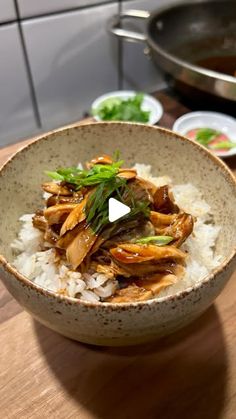 a bowl filled with rice and meat on top of a wooden table