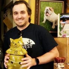 a man standing next to a yellow ceramic cat