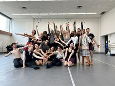 a group of people posing for a photo in an empty room with their arms up