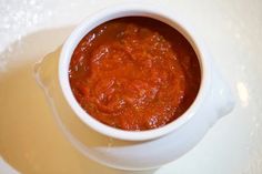 a white bowl filled with sauce on top of a table