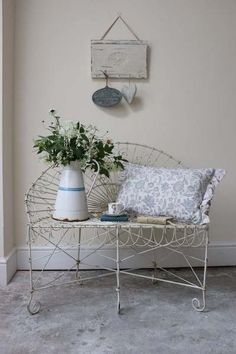 a white bench with two vases on top of it next to a wall hanging