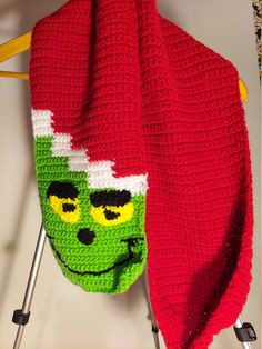 a crocheted grin face hat hanging on a clothes rack