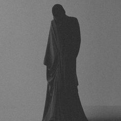 a black and white photo of a person standing in the fog with their back to the camera