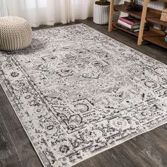 a large rug with an ornate design on the floor in front of a wooden table