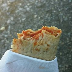 a piece of food sitting on top of a napkin in someone's left hand