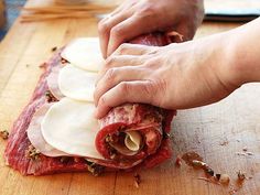 a person cutting up meat on top of a wooden table