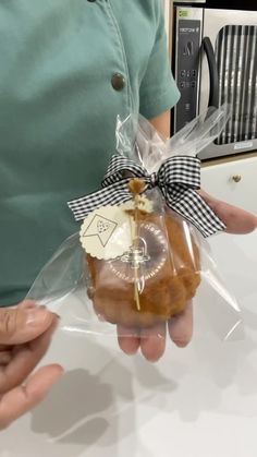 a person holding a piece of bread wrapped in cellophane and tied with a ribbon