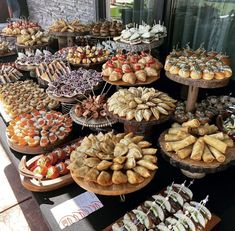 a table topped with lots of different types of pastries next to a window filled with windows